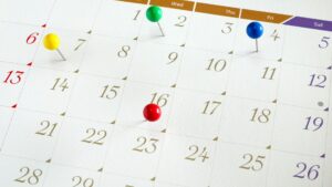 Close of of calendar, with different coloured pins on key dates